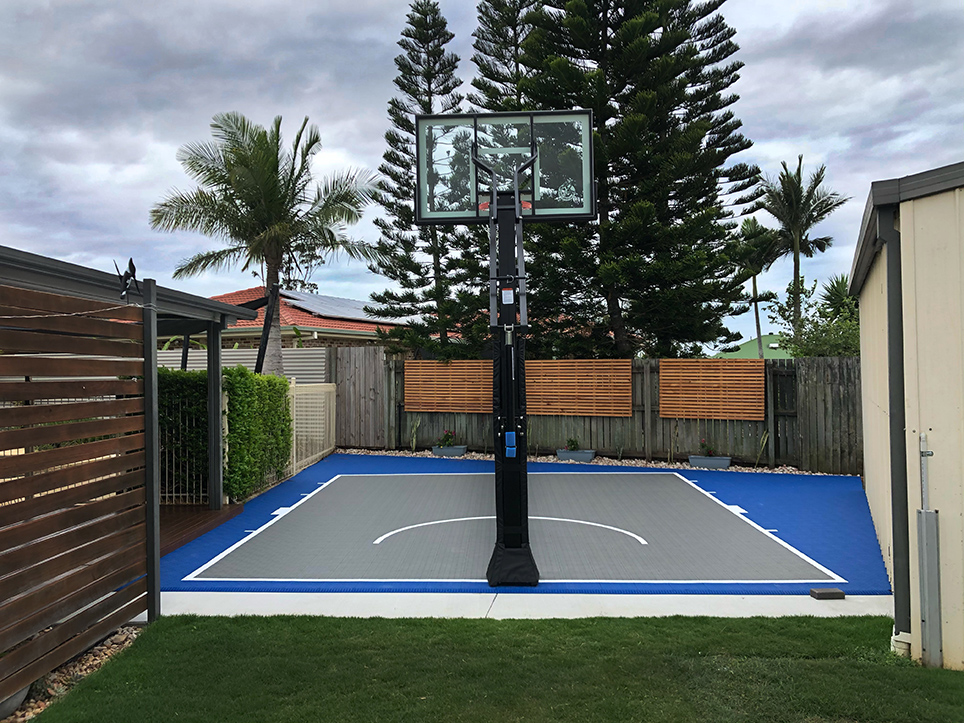 Half court basketball court next to a fence | Featured Image for the Backyard Basketball Court landing page.