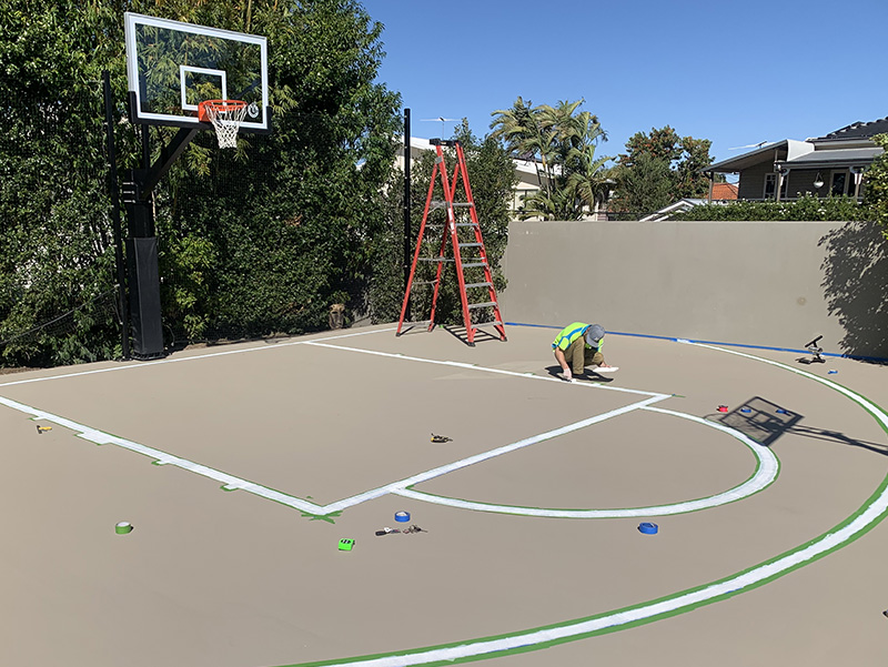 man painting lines on a basketball court