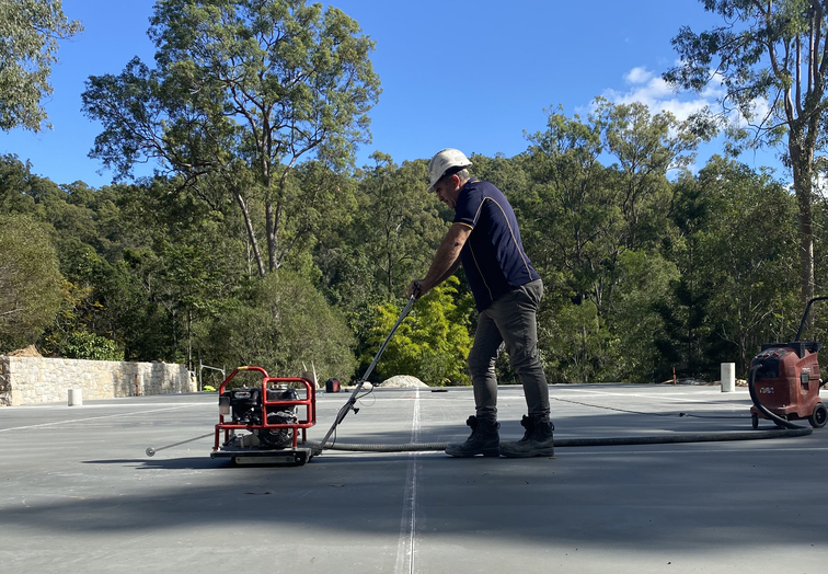 A man drawing line of a newly build tennis court with a machine | Featured Image of the Tennis Court Construction page